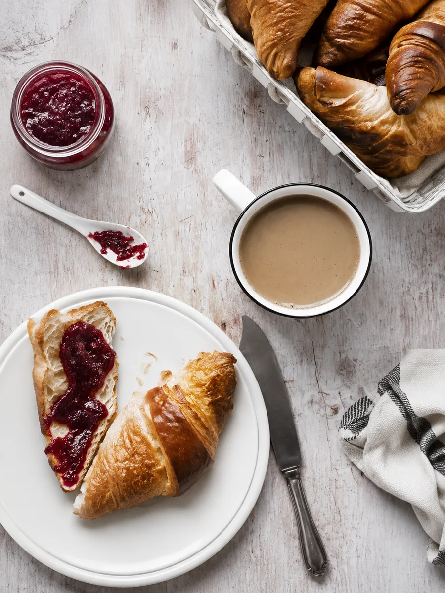 Croissants, raspberry jam and coffee on a table